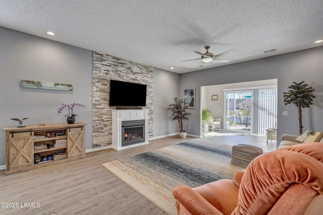 living room with light wood-style floors, a fireplace, and a textured ceiling