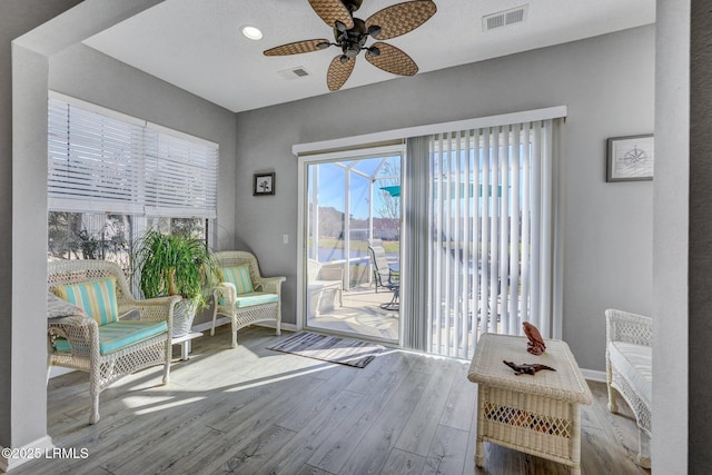 living area with a ceiling fan, light wood-type flooring, visible vents, and baseboards