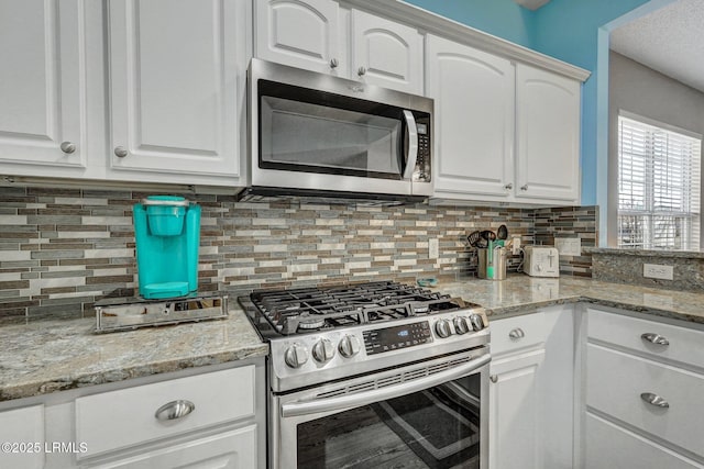 kitchen featuring white cabinets, light stone counters, and stainless steel appliances