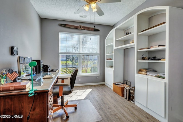 office with baseboards, visible vents, light wood-style flooring, ceiling fan, and a textured ceiling