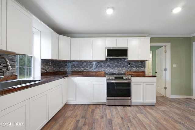 kitchen with sink, white cabinets, hardwood / wood-style flooring, stainless steel appliances, and crown molding