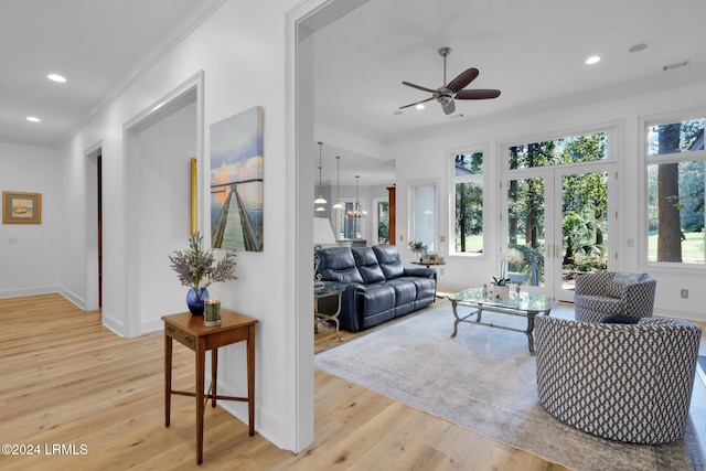 living room with crown molding, ceiling fan, and light hardwood / wood-style flooring