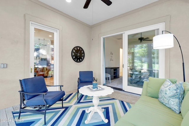 living room featuring hardwood / wood-style flooring, ornamental molding, and ceiling fan