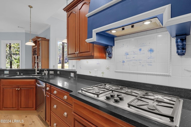 kitchen with decorative light fixtures, sink, backsplash, crown molding, and white gas cooktop