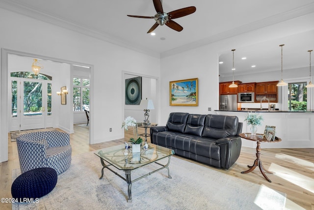 living room with ornamental molding, light hardwood / wood-style floors, and ceiling fan