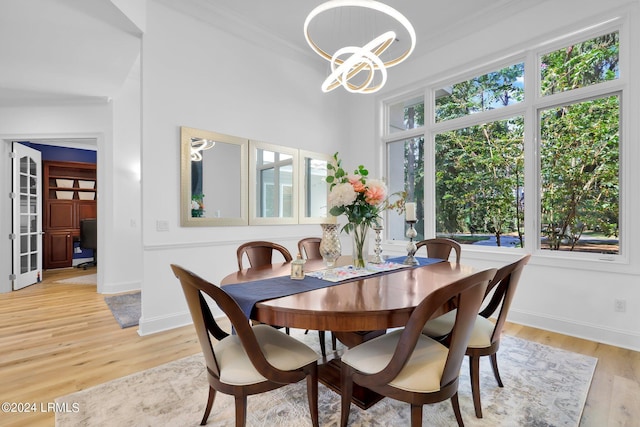 dining area with an inviting chandelier, light hardwood / wood-style flooring, and ornamental molding