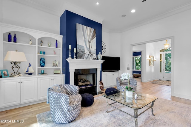 living room with ornamental molding, light hardwood / wood-style floors, and built in features