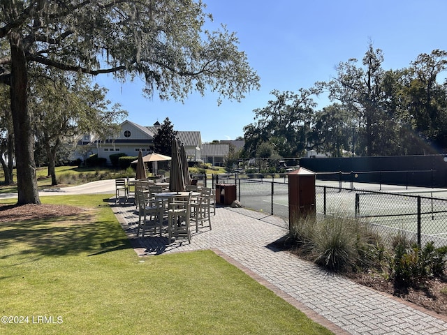 view of home's community featuring a yard and tennis court