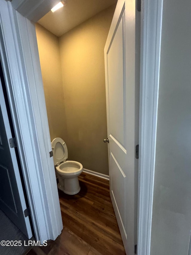 bathroom with toilet, wood finished floors, and baseboards