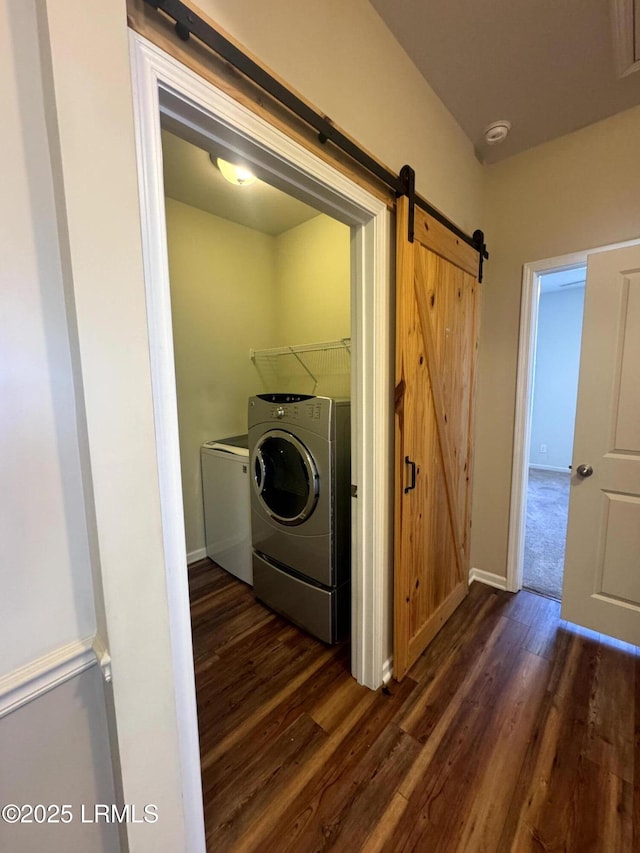 laundry area featuring dark wood finished floors, laundry area, independent washer and dryer, and a barn door