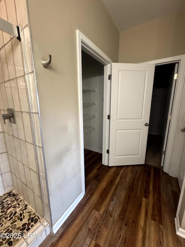 bathroom featuring baseboards, wood finished floors, and a shower stall