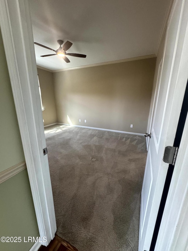 empty room with dark carpet, baseboards, ceiling fan, and ornamental molding