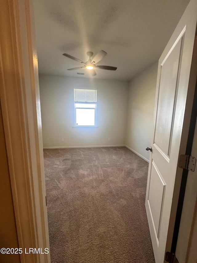 empty room with visible vents, baseboards, carpet, and ceiling fan