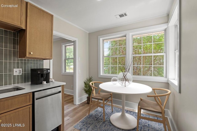 1730 Battery Park Dr, Port Royal, SC 29935 - kitchen with stainless steel dishwasher, crown molding, light wood-style flooring, light countertops, and decorative backsplash
