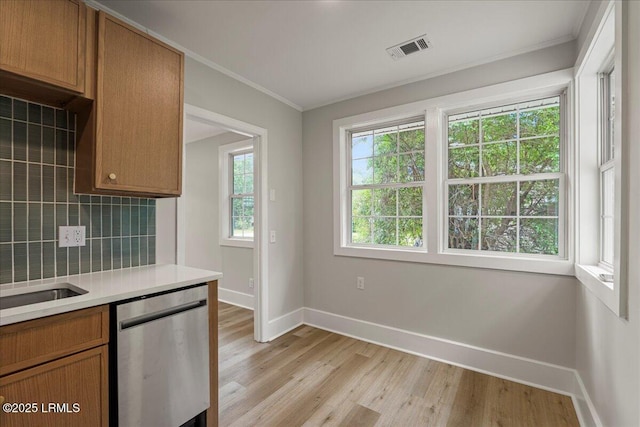 1730 Battery Park Dr, Port Royal, SC 29935 - kitchen with stainless steel dishwasher, light wood finished floors, decorative backsplash, ornamental molding, and light countertops