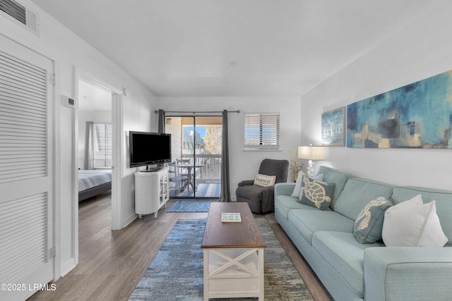 living area with wood finished floors, visible vents, and baseboards