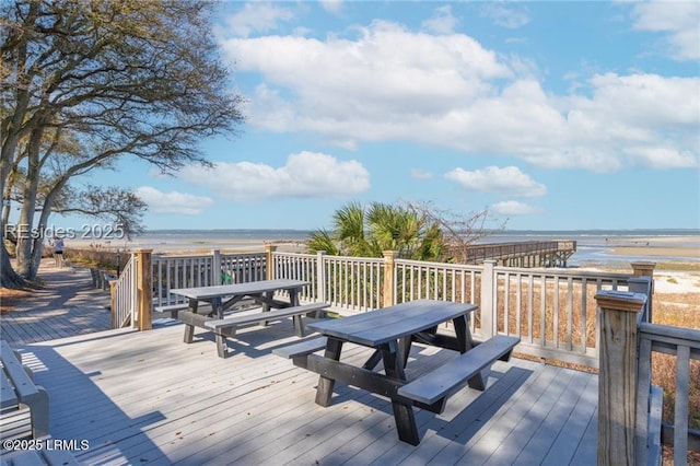 deck with a water view, a beach view, and outdoor dining space