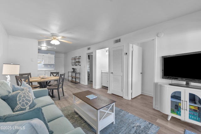 living area with baseboards, light wood-style flooring, visible vents, and a ceiling fan