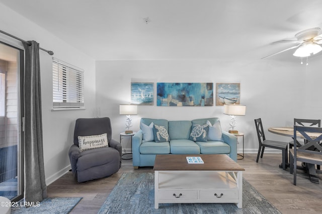 living room featuring ceiling fan, baseboards, and wood finished floors