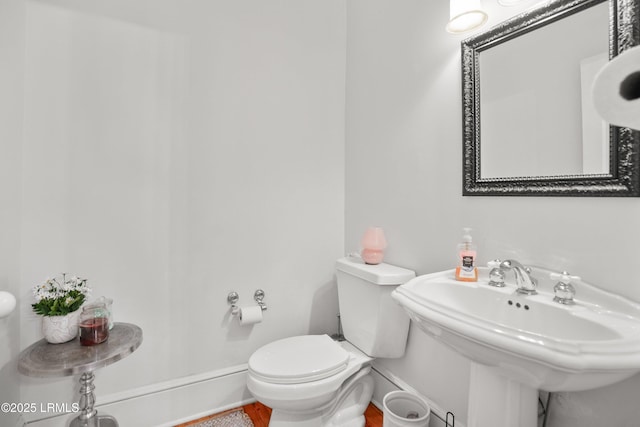 bathroom featuring toilet, baseboards, and a sink