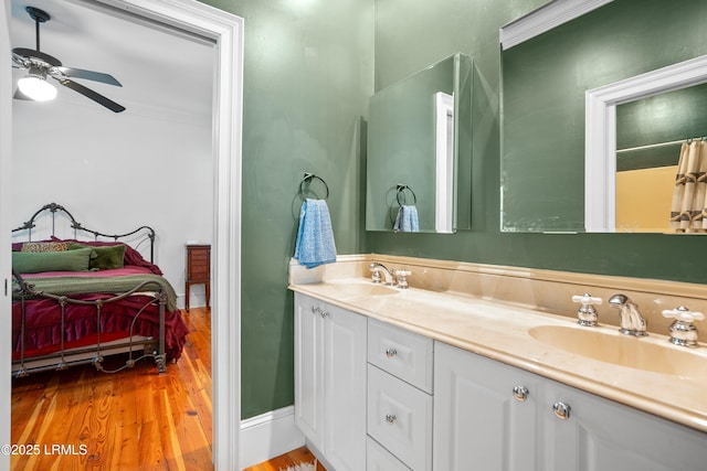 bathroom featuring connected bathroom, wood finished floors, a sink, and double vanity