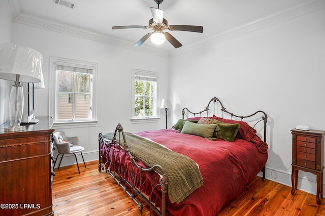 bedroom with visible vents, crown molding, baseboards, and hardwood / wood-style flooring