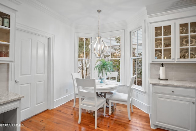 dining space with crown molding, light wood-type flooring, a notable chandelier, and plenty of natural light