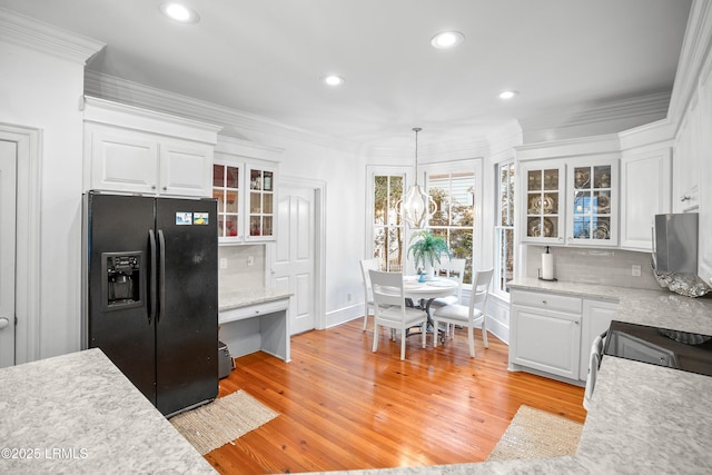 kitchen with black fridge with ice dispenser, glass insert cabinets, light countertops, white cabinetry, and pendant lighting