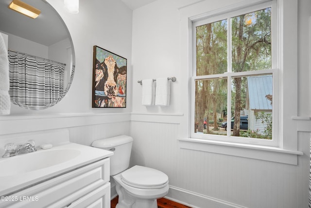 full bath featuring toilet, wainscoting, and vanity