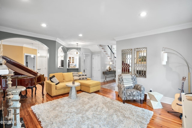 living area with crown molding, stairway, baseboards, and wood finished floors