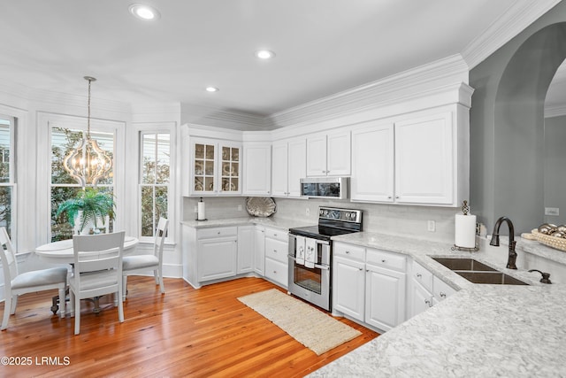 kitchen with stainless steel appliances, pendant lighting, white cabinets, and a sink