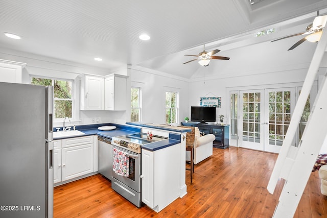 kitchen with stainless steel appliances, dark countertops, light wood-style flooring, and white cabinets