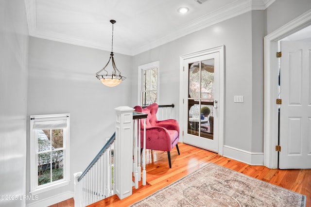 sitting room with ornamental molding, baseboards, light wood finished floors, and an upstairs landing