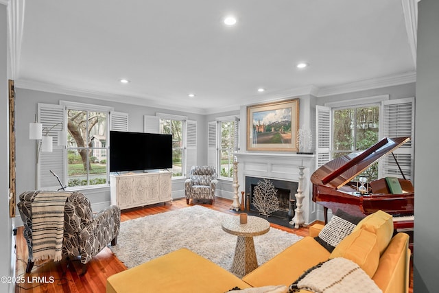 living area featuring crown molding, recessed lighting, a fireplace with flush hearth, wood finished floors, and baseboards