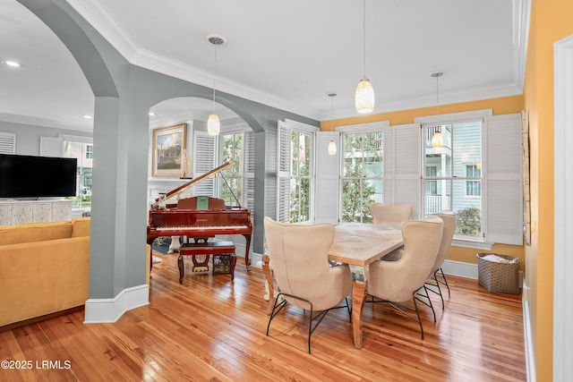 dining space featuring light wood-style flooring, baseboards, and crown molding