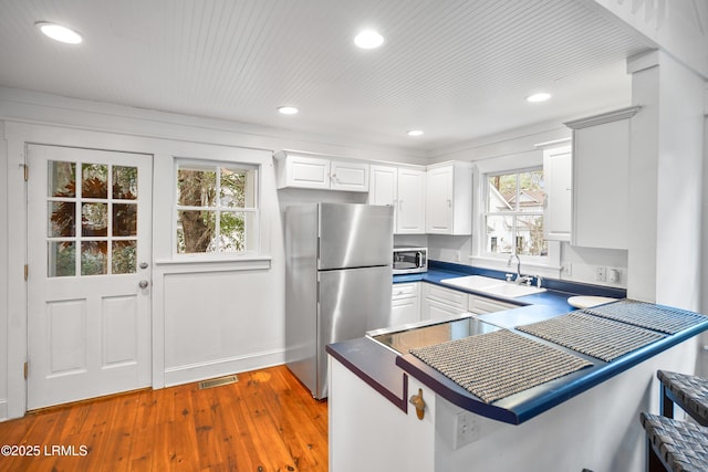 kitchen featuring stainless steel appliances, a sink, visible vents, white cabinets, and dark countertops