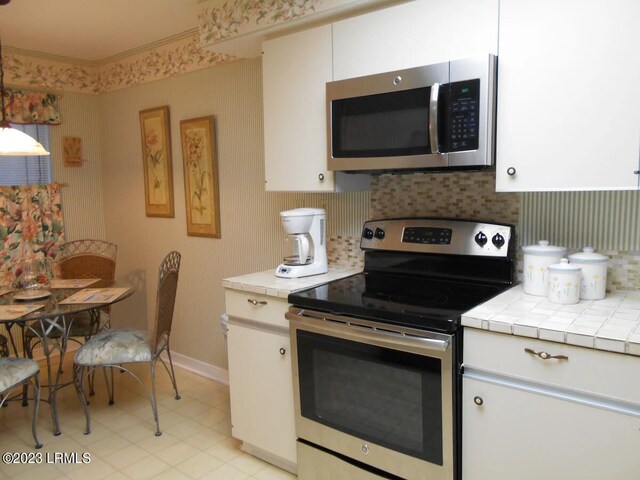 kitchen featuring white cabinetry, stainless steel appliances, tile counters, and tasteful backsplash