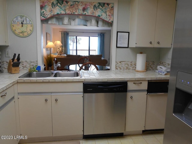 kitchen featuring sink, backsplash, stainless steel appliances, white cabinets, and tile countertops