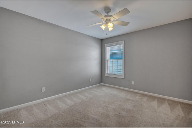 empty room with carpet flooring, a ceiling fan, and baseboards