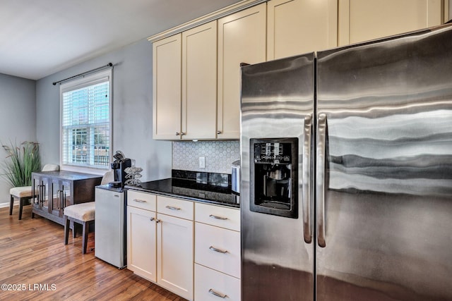 kitchen featuring dark stone counters, light wood-type flooring, backsplash, and stainless steel fridge with ice dispenser