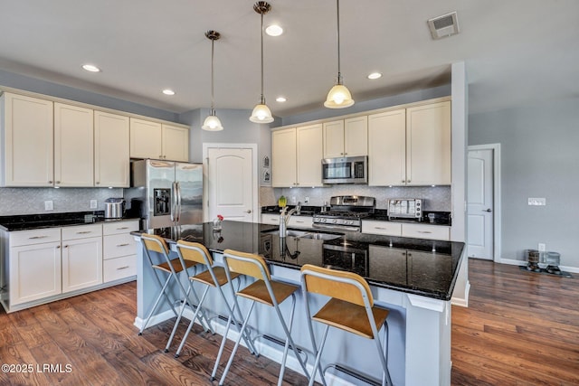 kitchen with dark wood-style floors, stainless steel appliances, hanging light fixtures, and visible vents