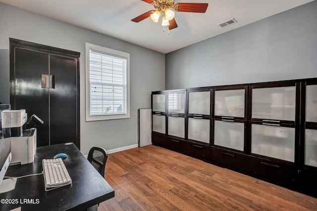 home office featuring a ceiling fan, visible vents, baseboards, and wood finished floors