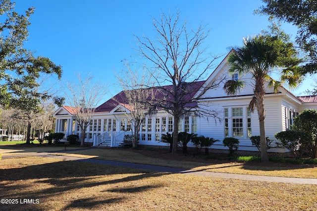 view of front of home with metal roof and a front lawn