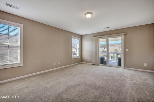 empty room with carpet floors, visible vents, and baseboards