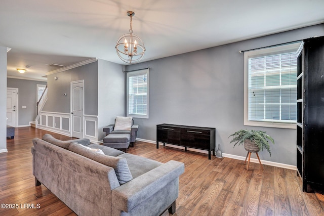 living area with stairway, a notable chandelier, baseboards, and wood finished floors