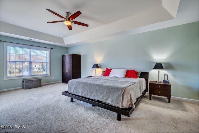 carpeted bedroom featuring a tray ceiling, visible vents, ceiling fan, and baseboards