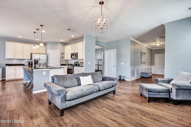 living area with a chandelier, recessed lighting, dark wood-style flooring, visible vents, and ornamental molding