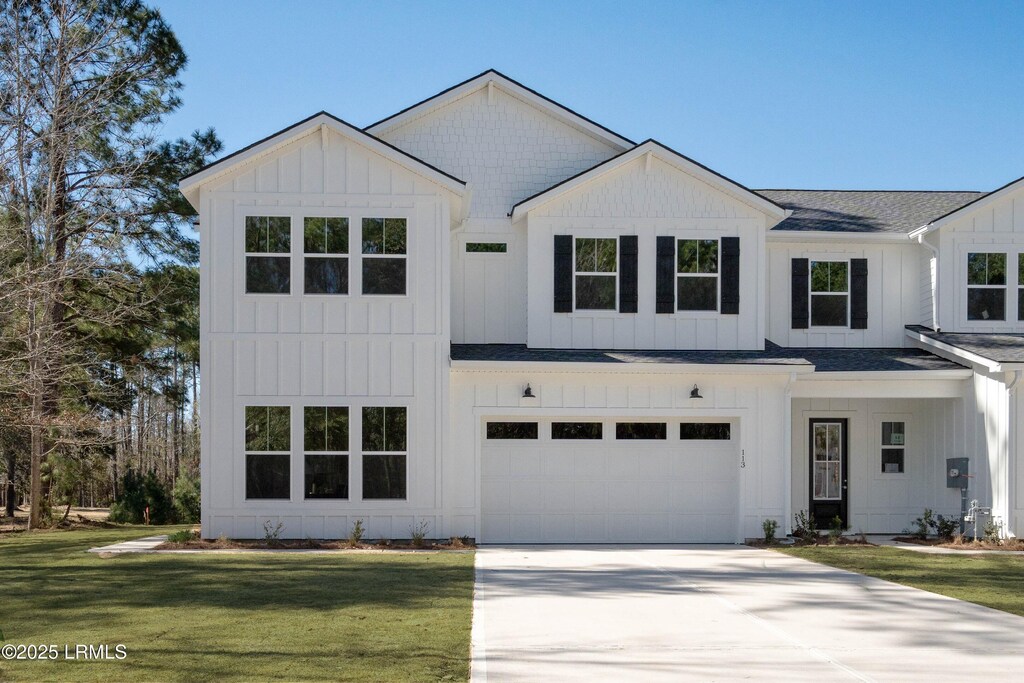 modern farmhouse with board and batten siding, a shingled roof, a front lawn, a garage, and driveway