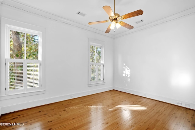 spare room featuring ornamental molding, visible vents, baseboards, and wood finished floors