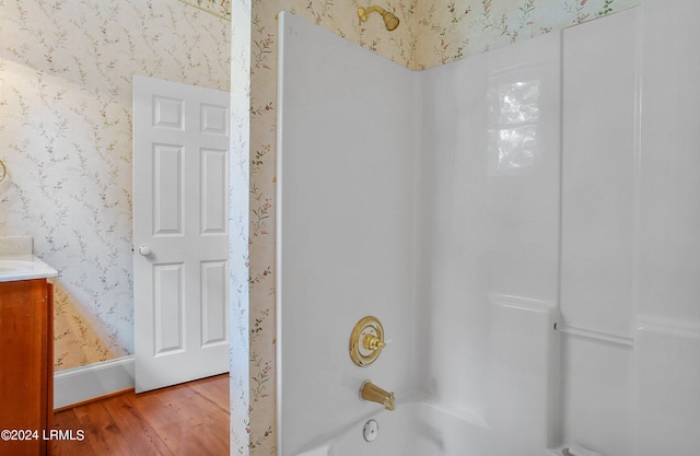 full bath featuring shower / bath combination, vanity, wood finished floors, baseboards, and wallpapered walls